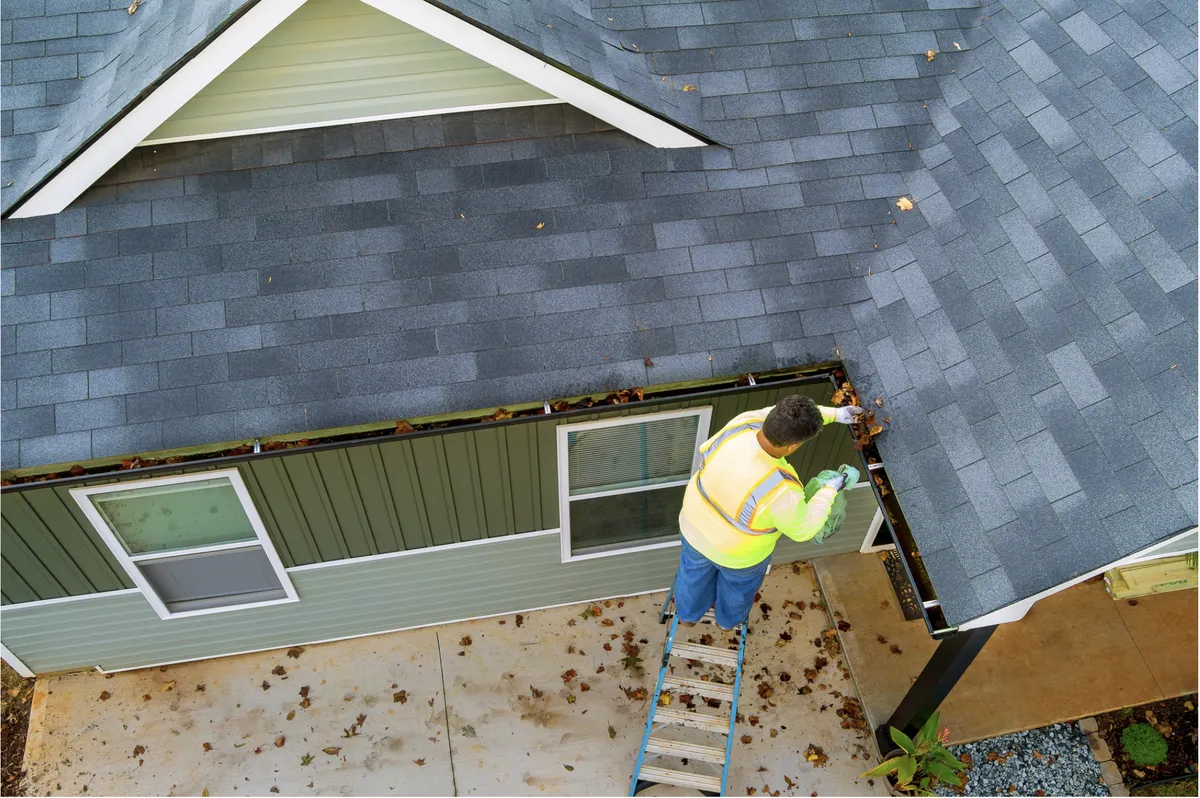 Professional gutter cleaning process showing debris removal and downspout flushing on a Galveston coastal home